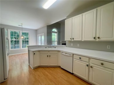 Kitchen with white appliances, a sink, light wood-style floors, white cabinets, and light countertops