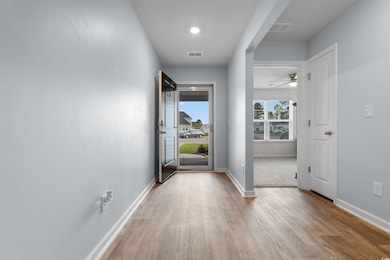 Hall featuring baseboards, visible vents, and wood