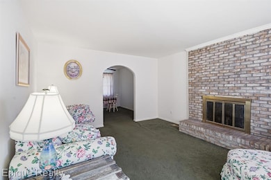 Living area featuring arched walkways, dark carpet, and a fireplace