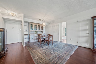 Dining area with a textured ceiling and dark wood-style floors