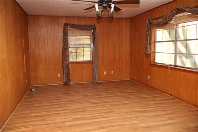 Unfurnished room featuring plenty of natural light, wood walls, light wood-type flooring, and ceiling fan