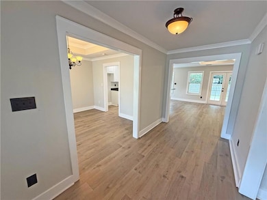 Hall featuring ornamental molding, a chandelier, and light wood-type flooring