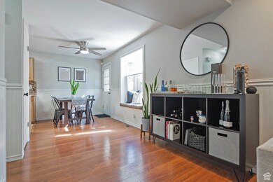 Dining area featuring a wainscoted wall, light wood-style floors, and ceiling fan