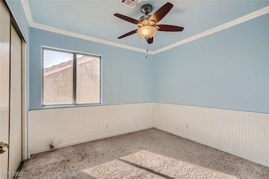 Carpeted empty room with wainscoting, a ceiling fa