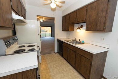 Kitchen with electric range oven, a textured ceiling, light countertops, under cabinet range hood, and dark brown cabinetry