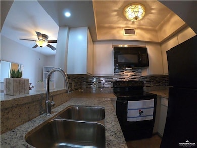 Kitchen with black appliances, a sink, a ceiling fan, backsplash, and white cabinets
