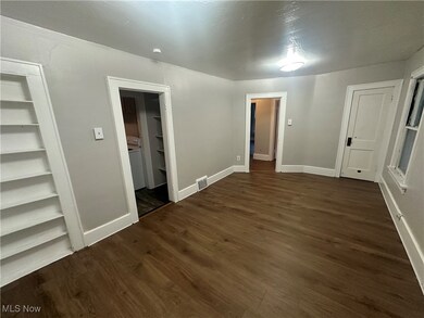 Empty room featuring dark wood-style floors and baseboards