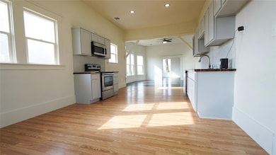 Kitchen featuring dark countertops, appliances with stainless steel finishes, gray cabinetry, light wood-style floors, and recessed lighting