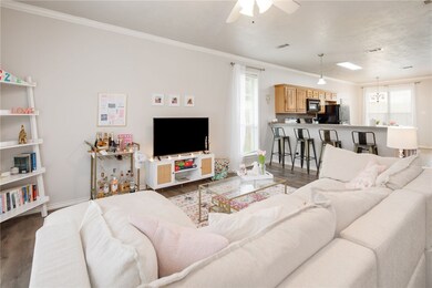 Living area with crown molding, a ceiling fan, woo