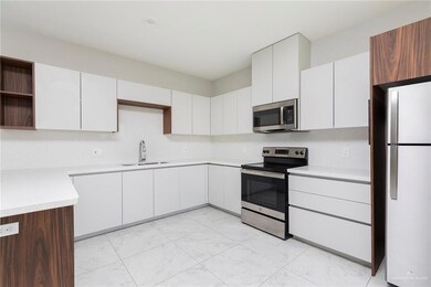 Kitchen with stainless steel appliances, a sink, open shelves, light marble finish floors, and light countertops
