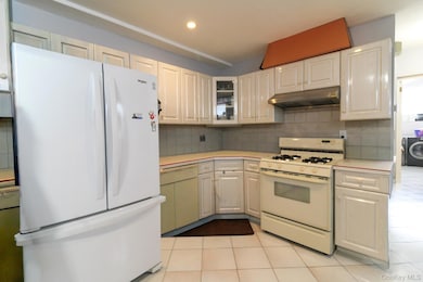 Kitchen featuring white appliances, light countertops, light tile patterned flooring, backsplash, and recessed lighting