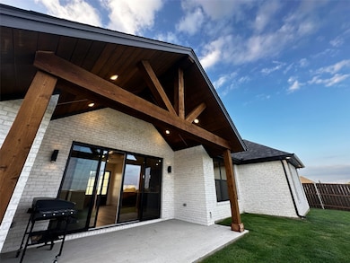 Rear view of property featuring brick siding, a yard, and a patio