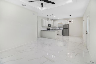 Kitchen featuring stainless steel appliances, ceiling fan with notable chandelier, light tile flooring, and white cabinetry