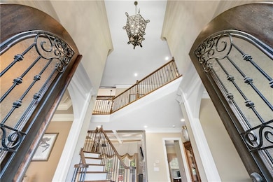 Step into a stunning two-story foyer, illuminated by a magnificent chandelier, creating an immediate impression of elegance and grandeur