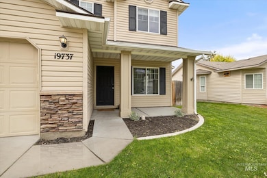Doorway to property featuring covered porch, a garage, a lawn, and stone siding