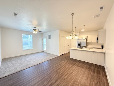 Spacious penninsula Kitchen with quartz countertops, pendant light fixtures and stainless steel microwave, dw, range and refrigerator with ice dispenser