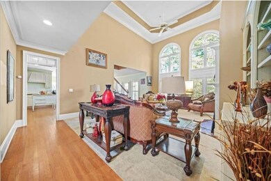 Living room featuring ornamental molding, light wood-type flooring, a towering ceiling, baseboards, and stairway