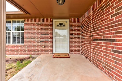 Property entrance featuring brick siding and covered porch