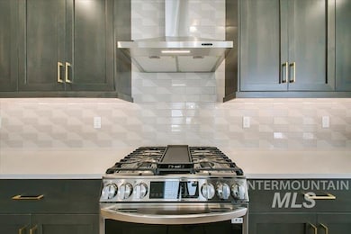 Kitchen featuring gas range, wall chimney exhaust hood, light countertops, and decorative backsplash