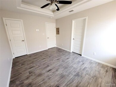 Unfurnished bedroom featuring a tray ceiling, dark wood-type flooring, and ceiling fan