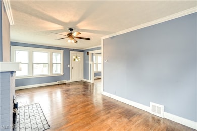 Unfurnished living room with ornamental molding, hardwood floors, and ceiling fan