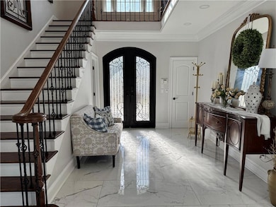 Entryway with arched walkways, baseboards, marble finish flooring, healthy amount of natural light, and crown molding