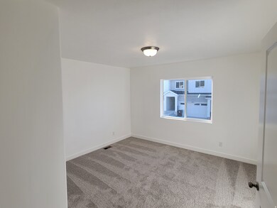 Empty room with light colored carpet and baseboards