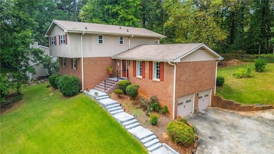 View of front of home featuring a front yard, brick siding, a garage, and driveway