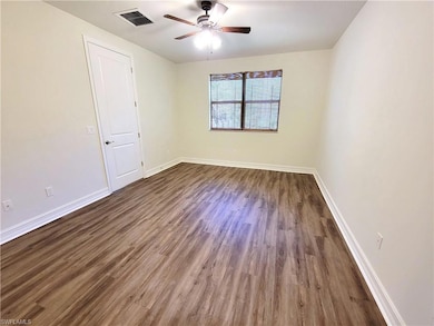Unfurnished room with dark wood-type flooring, ceiling fan, and baseboards