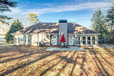 Back of house with a chimney, a shingled roof, a patio area, and stucco siding