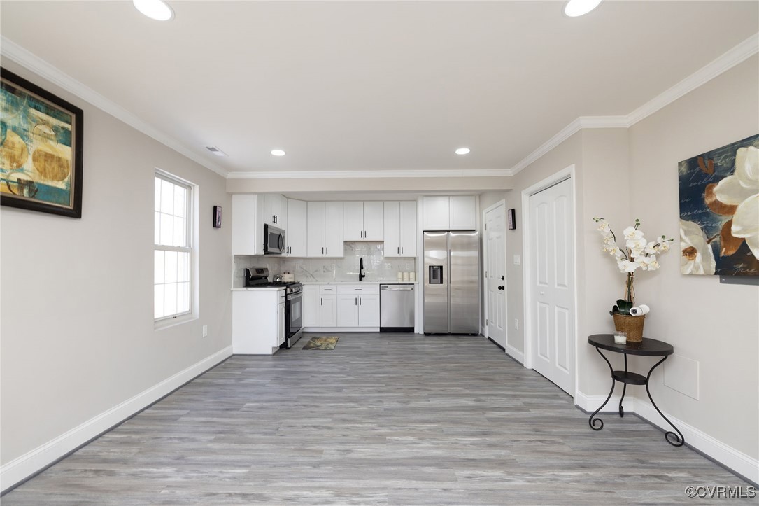 Kitchen with crown molding, white cabinetry, backs
