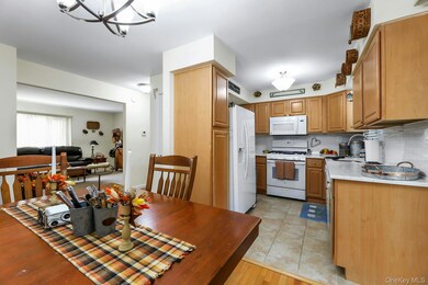Kitchen with white appliances, backsplash, a chandelier, light stone counters, and light wood-type flooring