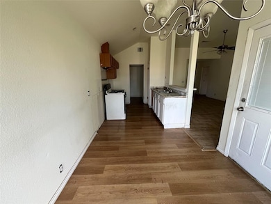 Kitchen featuring a chandelier, lofted ceiling, white gas range oven, light wood-type flooring, and light countertops
