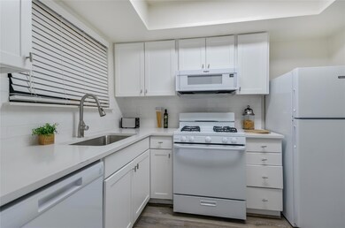 Kitchen with white appliances, white cabinets, de