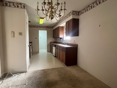 Kitchen with a chandelier, dark brown cabinets, a textured ceiling, dark countertops, and stainless steel dishwasher