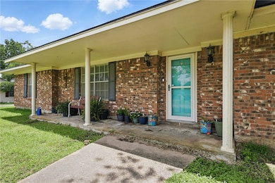 Entrance to property featuring covered porch, bric
