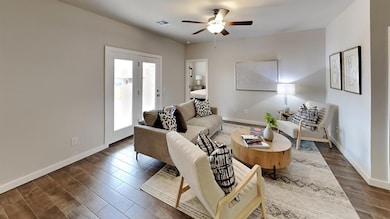 Living room with ceiling fan and dark wood-style flooring