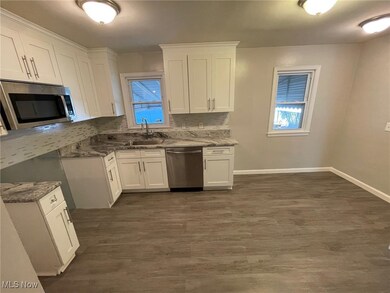 Kitchen featuring dark stone countertops, white cabinetry, appliances with stainless steel finishes, and dark wood-type flooring