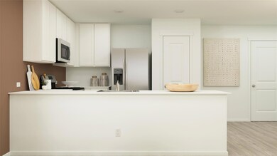 Kitchen with appliances with stainless steel finishes, kitchen peninsula, light wood-type flooring, and white cabinets