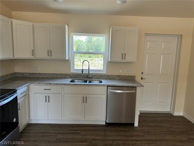 Kitchen featuring dark hardwood / wood-style floors, range with electric stovetop, white cabinetry, stainless steel dishwasher, and sink