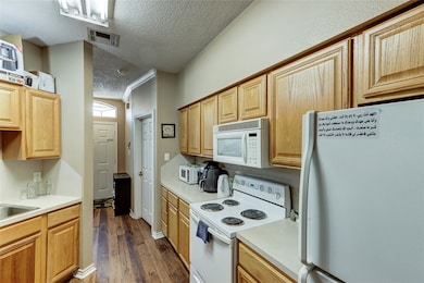 Kitchen featuring white appliances, a textured cei