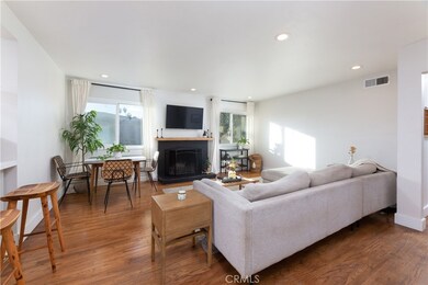 Entrance into living room with original hardwood floors, recessed lighting, warm cozy fireplace with mantle.