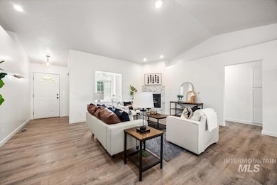 Living area with vaulted ceiling, light wood-style flooring, a tiled fireplace, and recessed lighting