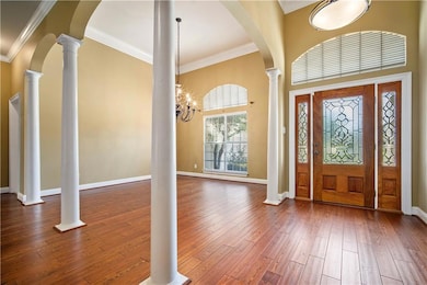 Entryway featuring ornamental molding, decorative columns, hardwood / wood-style flooring, and arched walkways