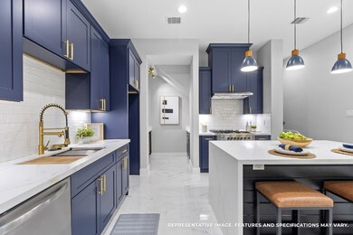 Cooking feels effortless with the sleek navy cabinetry, gold fixtures, and plenty of counter space to spread out and create.