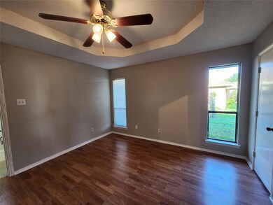 Unfurnished room with ceiling fan, a raised ceiling, wood-type flooring, and plenty of natural light