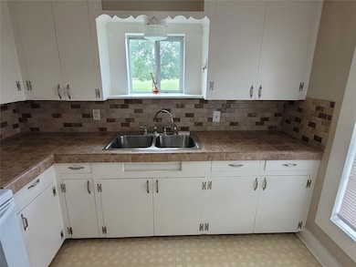 Kitchen featuring a sink, white cabinets, and bac