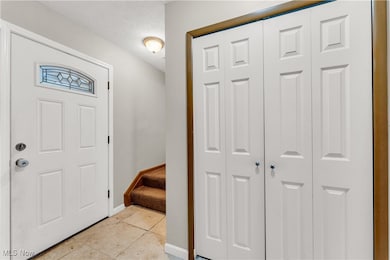 Entryway with light tile patterned floors, stairs, and a textured ceiling