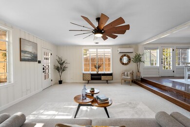 Carpeted living area featuring healthy amount of natural light, a ceiling fan, and a wall mounted AC