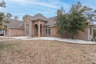 Traditional home with brick siding, a shingled roof, a chimney, and a front lawn